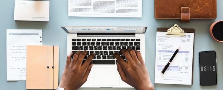 Top-down view of accountant working on a laptop at his desk.